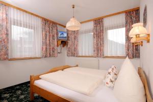 ein Schlafzimmer mit einem Bett und Fenster mit Vorhängen in der Unterkunft Haus Leonhard in Tux