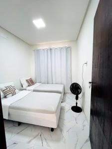 a white bedroom with two beds and a desk at Casa de condomínio em Paripueira com piscina e perto da praia in Paripueira