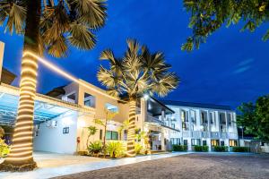 een gebouw met palmbomen ervoor bij Phuket Leisure Time Hotel in Rawai Beach