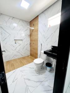 a white bathroom with a toilet and a piano at Casa de condomínio em Paripueira com piscina e perto da praia in Paripueira +28 photos