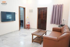 ein Wohnzimmer mit einer Couch, einem Tisch und einem Fernseher in der Unterkunft Cozy Homes, Tiruvannamalai in Tiruvannāmalai + 15 Fotos
