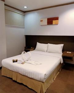 a bedroom with a large bed with white sheets at Magallanes Square Hotel Inc. in Tagaytay +10 photos