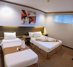 a hotel room with two beds with white sheets at Magallanes Square Hotel Inc. in Tagaytay