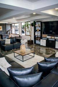 a living room with black leather furniture and a large tv at Spa la casona de pirque in Pirque