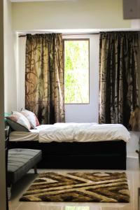 1 cama en un dormitorio con cortinas y ventana en Comfort Homey Studio with Fresh Mountain Air by Cherisia's Hideaway, en Baguio