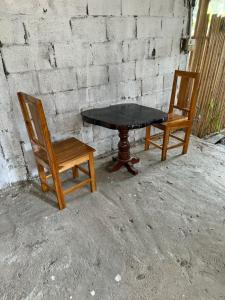 een tafel en twee stoelen naast een stenen muur bij KP Backpackers Hostel in Nongkhiaw