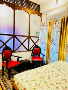 Un dormitorio con dos sillas rojas y una cama. en The Divine Abode Homestay, en Guwahati