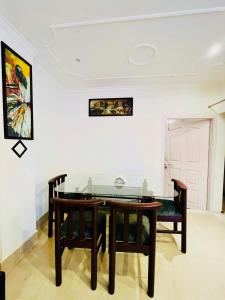 comedor con mesa de cristal y 2 sillas en The Divine Abode Homestay, en Guwahati