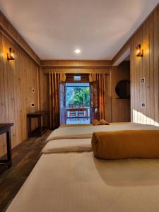 een slaapkamer met drie bedden met houten lambrisering bij Tea Brook Lodge Ella in Ella