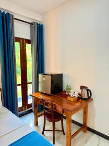 a bedroom with a desk with a television and a bed at Devon Surf . Inn - Hiriketiya in Dickwella