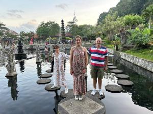 ウブドにあるMade Sura Bali Driver & Tourの池の飛び石の上に立っている男性と女性