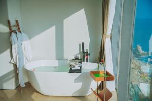 a white bath tub in a bathroom with a window at Qingdao Momer Cliff Ocean View Villas in Qingdao
