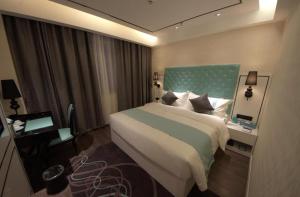 a bedroom with a large bed with a blue headboard at Xana Lite Korla Xiangli Avenue Food Street in Korla