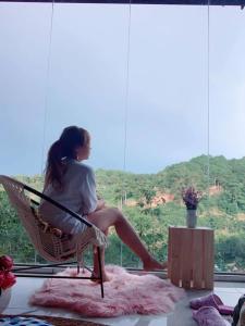 a woman sitting in a chair looking out a window at Roxie home view thung lũng,săn mây, gần trung tâm in Xuan An