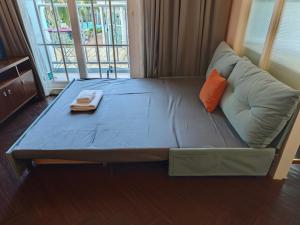 a bed in a room with a couch with an orange pillow at Grand Florida芭提雅带免费游泳池温泉和健身房和办公区水上花园公寓E208 in Na Jomtien