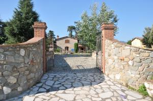 une clôture en pierre avec un portail en face d'une maison dans l'établissement Mugello Vacanze Appartamenti Indipendenti, à Scarperia