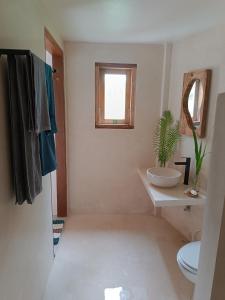 a bathroom with a sink and a toilet and a window at Sonnenhouse Lombok Kertaraharja in Luk