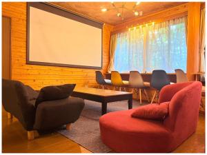 a meeting room with chairs and a large screen at コテージちゃ豆ん家 in Nasu