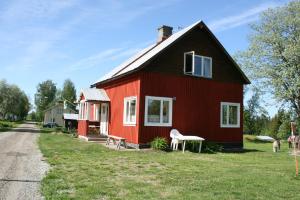 a red house with a white chair in front of it at Lillvikens Gästhuset och Stugor in Nedre Lillviken