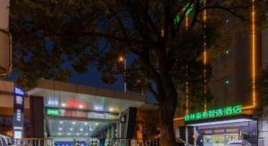 ein Gebäude mit einem Baum davor in der Unterkunft Green Tree Inn Hefei Railway Station International Auto Market Zhusitan Metro Station in Hefei