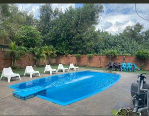 a swimming pool with white chairs and a blue poolvisor at Casa Melaka in Kampong Pulau Sebang