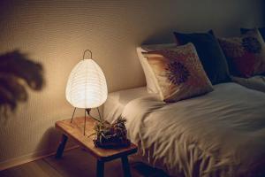 eine Lampe auf einem Tisch neben einem Bett in der Unterkunft reたたみのお宿 in Chikusachō