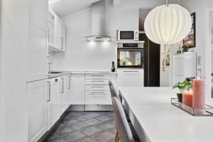 een keuken met witte kasten en een grote witte tafel bij Lovely Holiday Home Near Hasmark Beach in Otterup