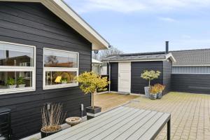 een zwart huis met een patio met potbomen bij Lovely Holiday Home Near Hasmark Beach in Otterup +20 foto's