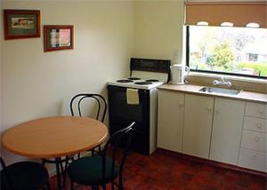 a kitchen with a table and a stove and a sink at Raceway Motel in Christchurch