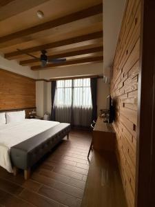 Un dormitorio con una cama y un escritorio y una ventana. en Gaodiyuan Tea B&B 高帝園茶業民宿, en Meishan