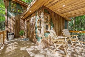 a wooden cabin with two chairs on a deck at Treehouse - Amazonia - Red River Gorge KY in Rogers