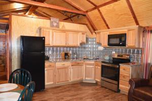 a kitchen with wooden cabinets and a black refrigerator at Secluded Getaway on a Vineyard in Allen, Oklahoma in Allen
