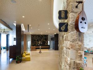 a lobby with a guitar hanging on a stone wall at Legacy Hotel ַ& Convention Center Nazareth in Nazareth