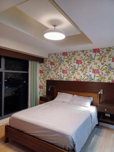 une chambre avec un grand lit avec un papier peint fleuri dans l'établissement 1bedroom suite 50th floor with balcony and bathtub at Horizons 101 tower 1, à Cebu