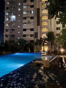 une piscine la nuit avec un grand immeuble dans l'établissement 1bedroom suite 50th floor with balcony and bathtub at Horizons 101 tower 1, à Cebu