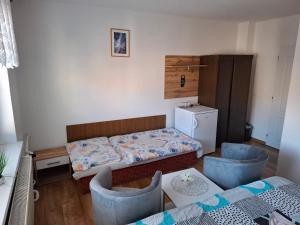 a small room with a bed and two chairs at Penzion MAYKA in Hrabušice