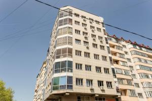 a tall white building with windows at Apart Comfort Almaty in Almaty