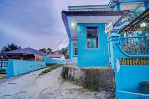 a blue house with a sign in front of it at Hotel O Adela in Laguboti