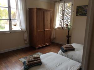 1 dormitorio con 2 camas, armario y ventanas en Maison Lajus en Bassillon-Vauzé