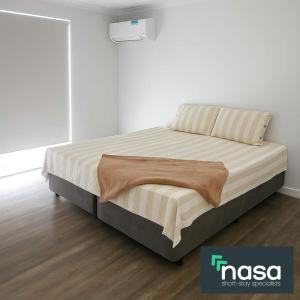 a bed in a white room with a white wall at Milbridge Getaway with a bathroom in each room in Eaton