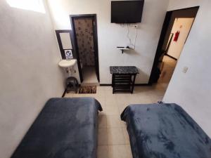 a room with two beds and a sink and a television at Hotelito Ejido in Sanctórum
