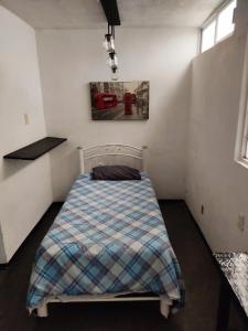 een slaapkamer met een bed met een geruite deken bij Hotelito Ejido in Sanctórum