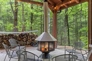 a porch with chairs and a lamp and a pile of logs at The Overlook - Camping Cabin Retreat in RRG KY in Rogers
