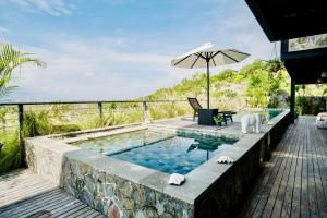 einen Außenpool mit Sonnenschirm, Tisch und Stühlen in der Unterkunft Mar de Uluwatu - Ocean View Villa in Uluwatu