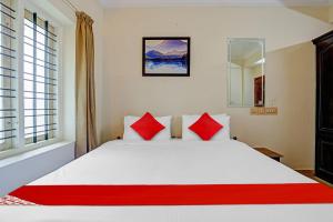 a bedroom with a white bed with red pillows at Hotel O Le Fort in Trivandrum +24 photos
