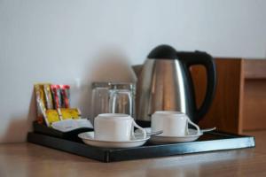 a tray with two cups and a tea kettle at San Antonio Beach Guesthouse & Restaurant in Kata Beach