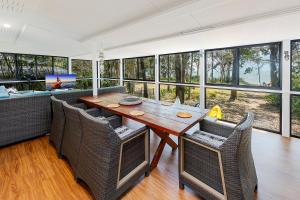 a dining room with a table and chairs and windows at Pet friendly beachfront home- sleeps 8 in Toogoom