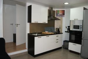 cocina con armarios blancos y encimera negra en Studio d'hôtes Villa Castelnau en Castelnau-le-Lez