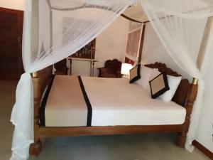 a bedroom with a bed with mosquito nets at T N D House in Habaraduwa Central