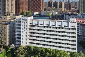 a large white building in a city with tall buildings at Fairfield by Marriott Shanghai Xuhui Center in Shanghai
